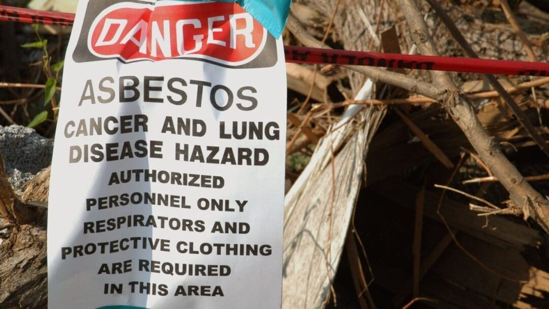 An asbestos warning sign posted in front of a demolition site where EnviroPro 360 was performing an asbestos inspection